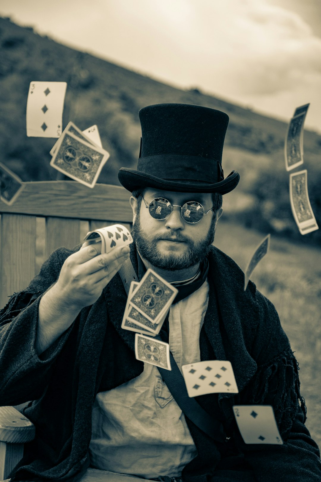 a-man-wearing-a-top-hat-and-glasses-holding-playing-cards-fiklocmnhiw